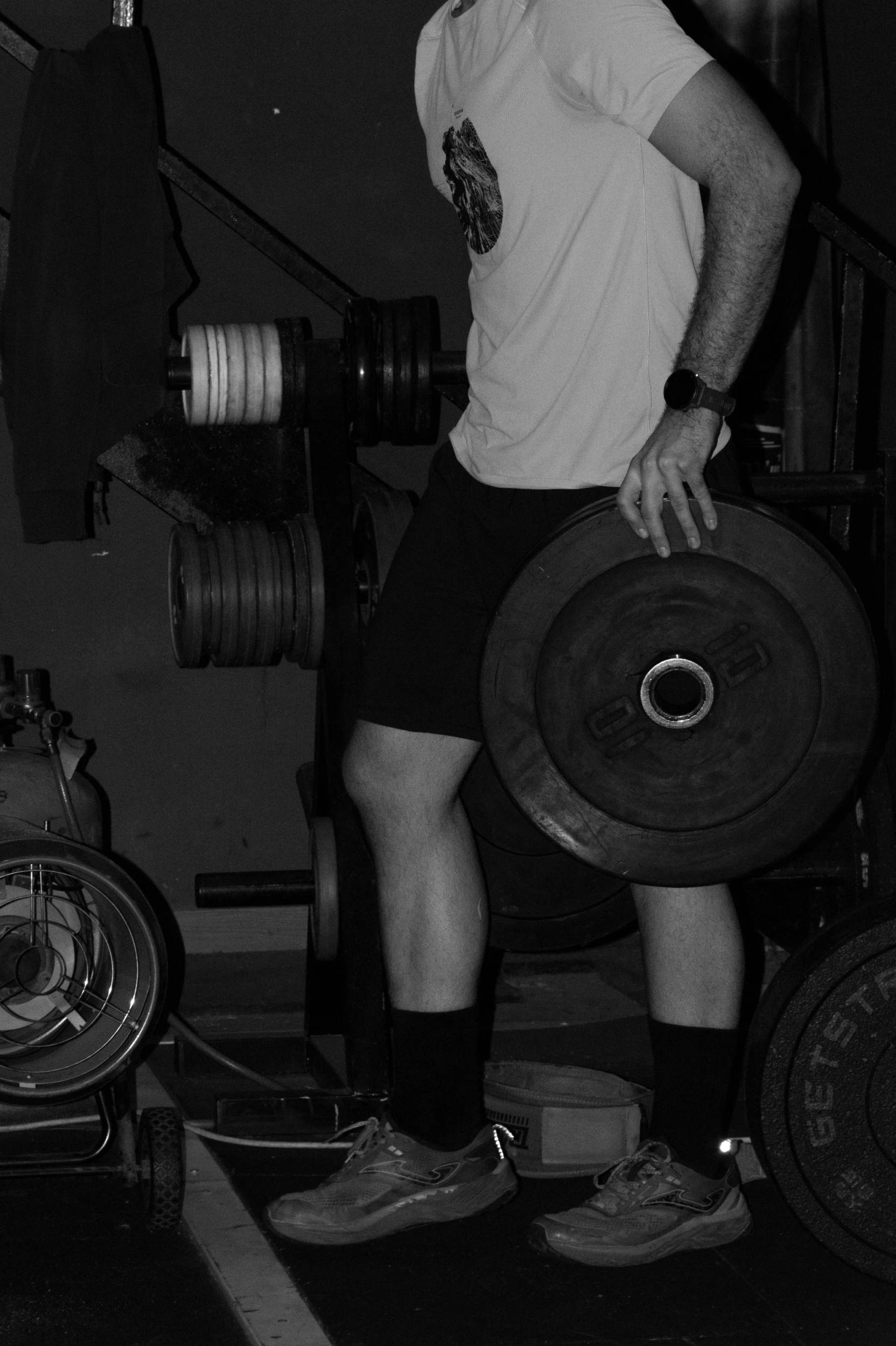 Foto en blanco y negro con una persona sujetando un disco de peso